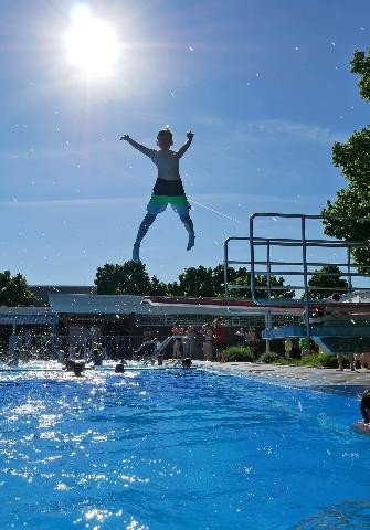 Kind springt vom 1 m Brett des Freibades ins Wasser