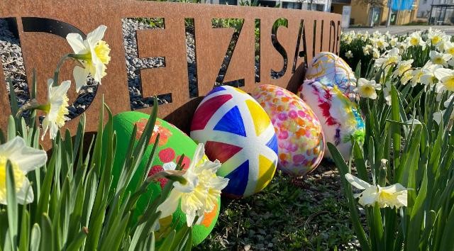 Bilder von den fünf gestalteten Ostereiern zwischen Narzissen